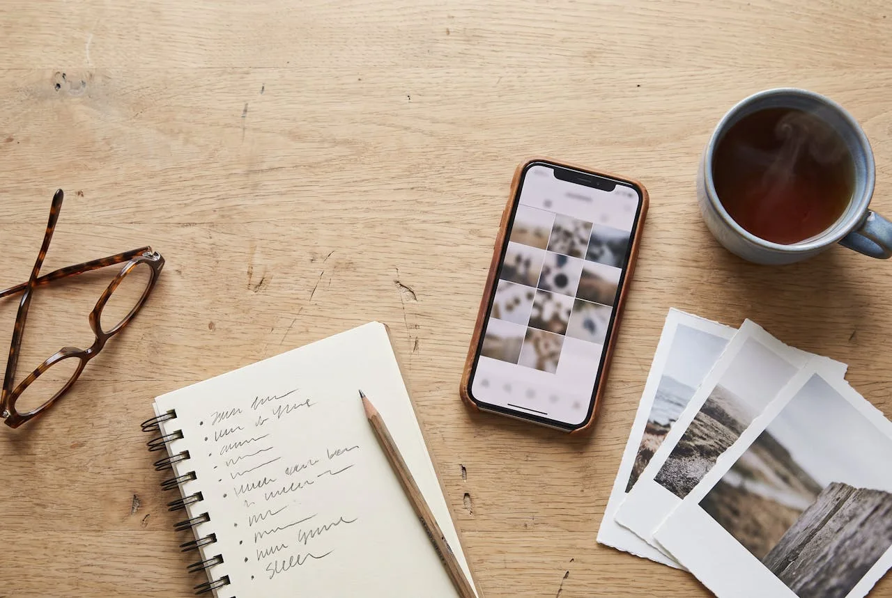 Bureau van bovenaf met telefoon, afgedrukte foto’s en een notitieblok